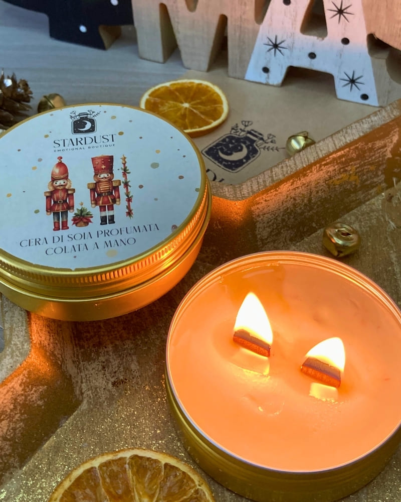 Candela profumata regalo Natalizio in contenitore circolare color oro da 100g con due stoppini in legno. Etichetta illustrata con due schiaccianoci giocattolo natalizi.