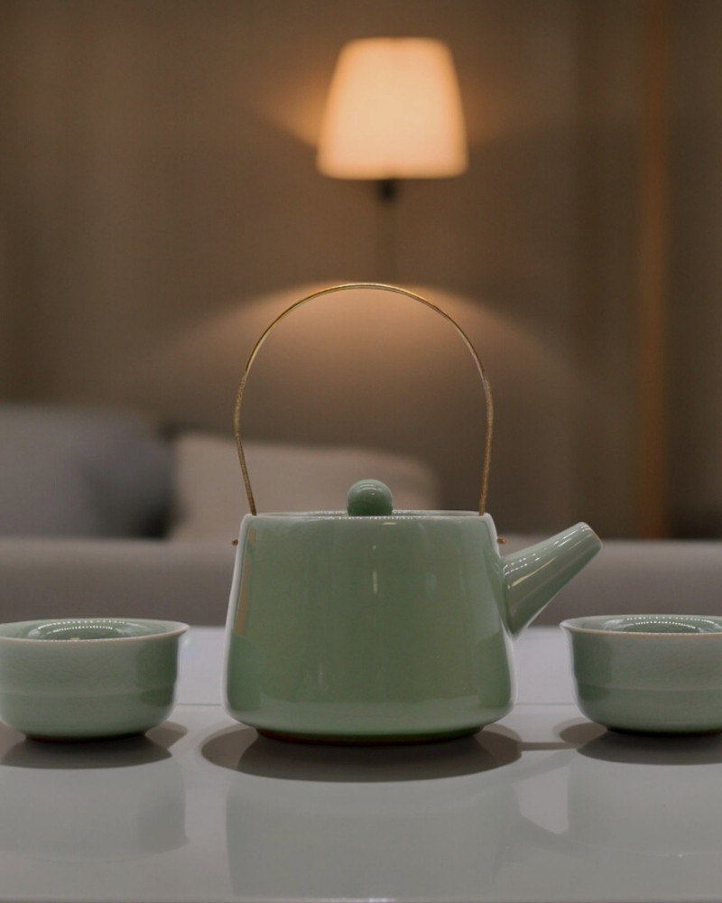 Teiera verde con due tazze in ceramica minimal su tavolo elegante